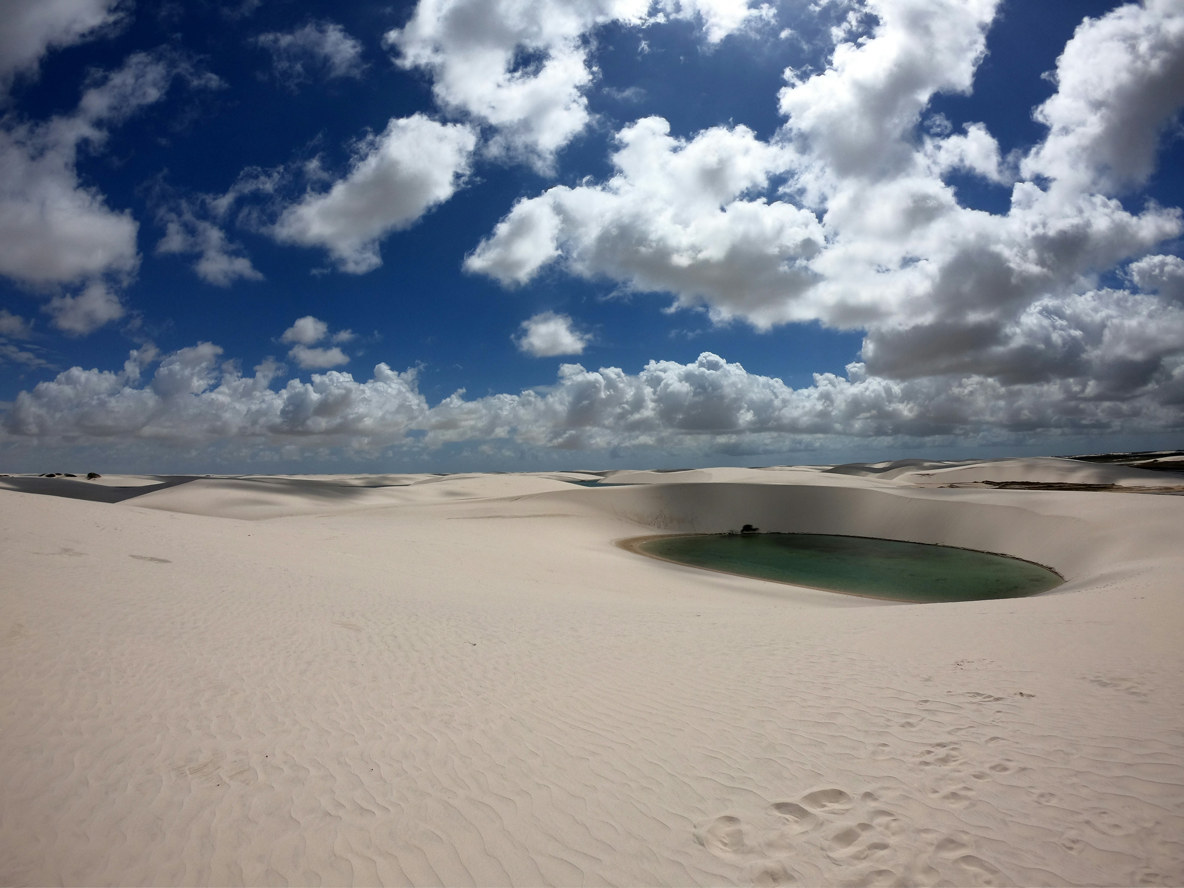 Emerald lagoon surrounded by white sand dunes