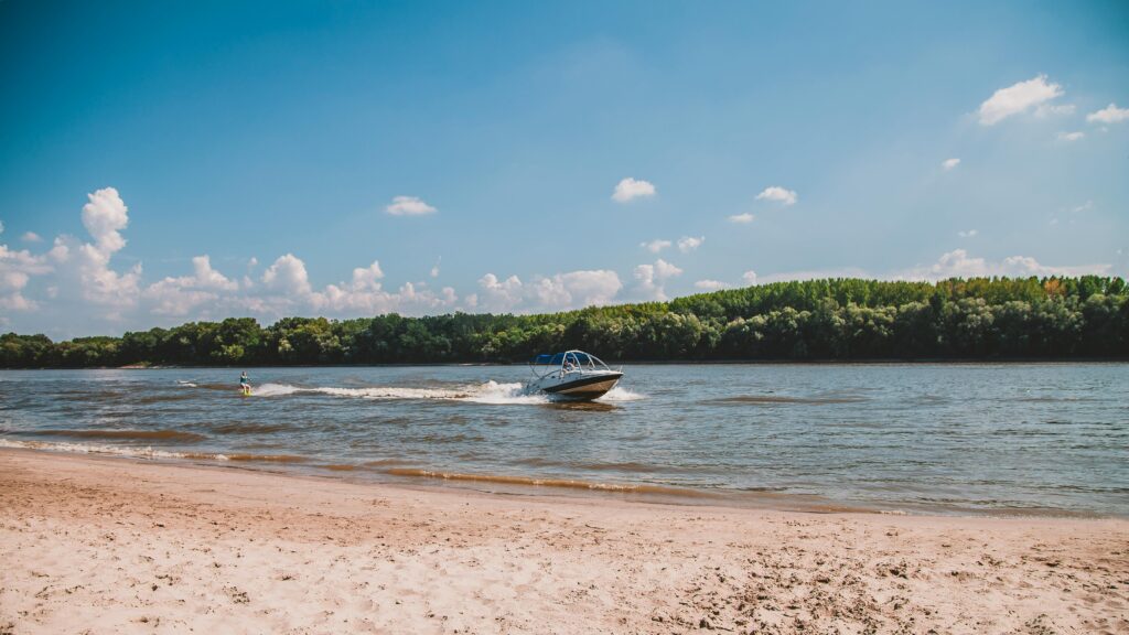 pexels-photo-1322086-1322086 A speedboat gliding across calm waters near a sandy beach under a clear blue sky.