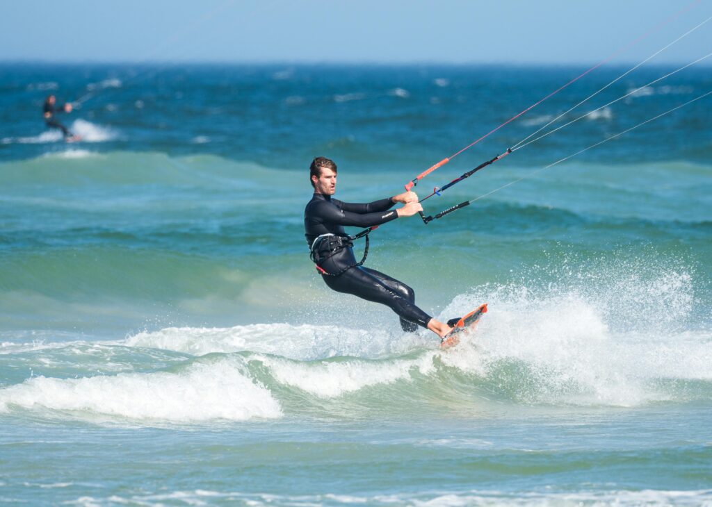 pexels-photo-1547703-1547703 A skilled kiteboarder navigates thrilling waves on a sunny day at the ocean.