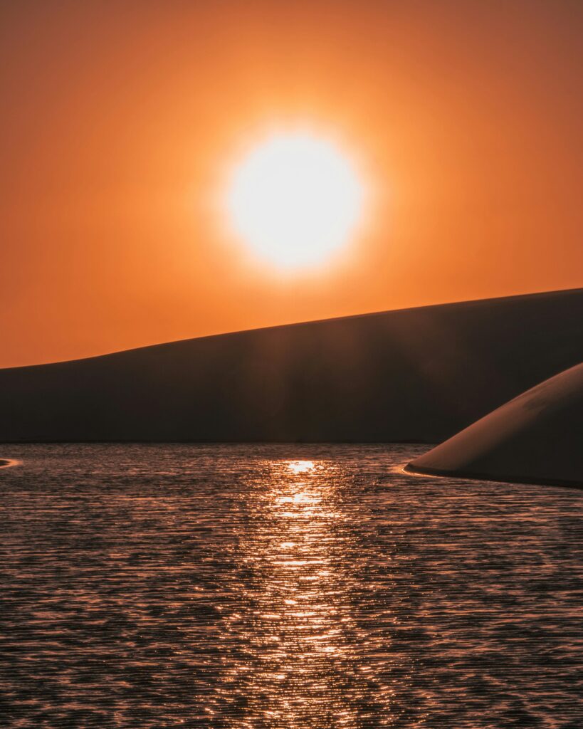 Capture of a breathtaking sunset over dunes and water in Atins, Brazil, highlighting nature's beauty.