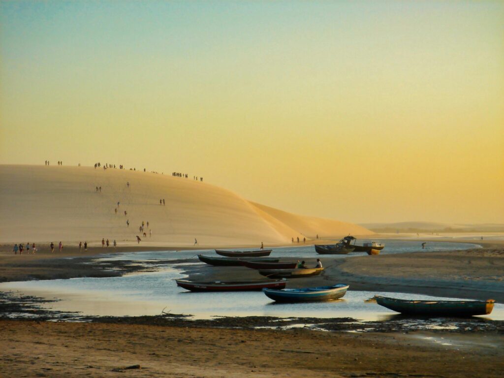 Stunning sunset view of boats and sand dunes at Jericoacoara Beach, Brazil.