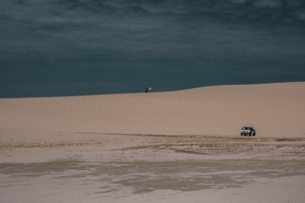 pexels-photo-7431247-7431247 Jeep navigating the sandy dunes of Jericoacoara desert under a cloudy sky.