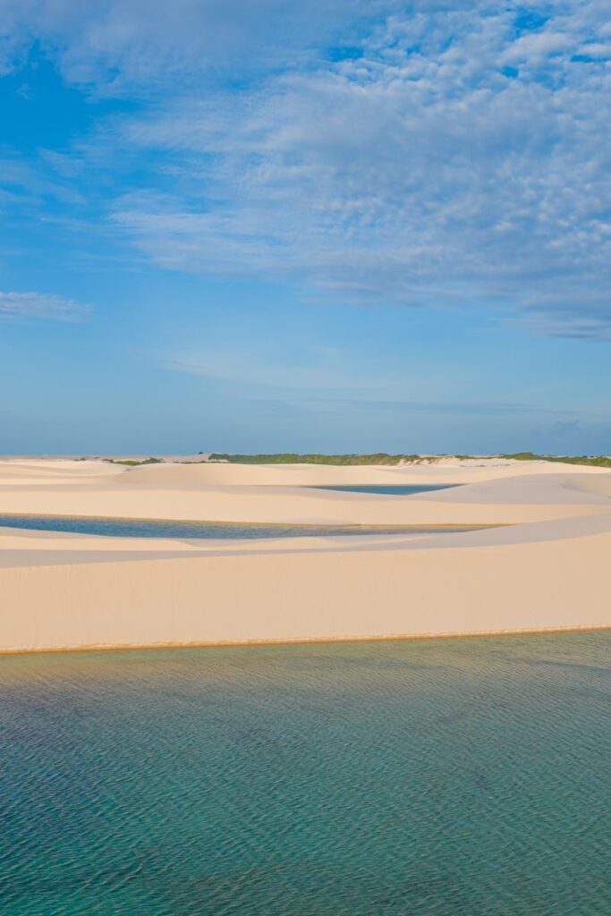 Explore the surreal beauty of Lençóis Maranhenses, Brazil with tranquil lagoons and sandy dunes.